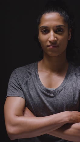 Vertical-Video-Studio-Portrait-Of-Woman-Wearing-Sports-Clothing-Against-Dark-Background